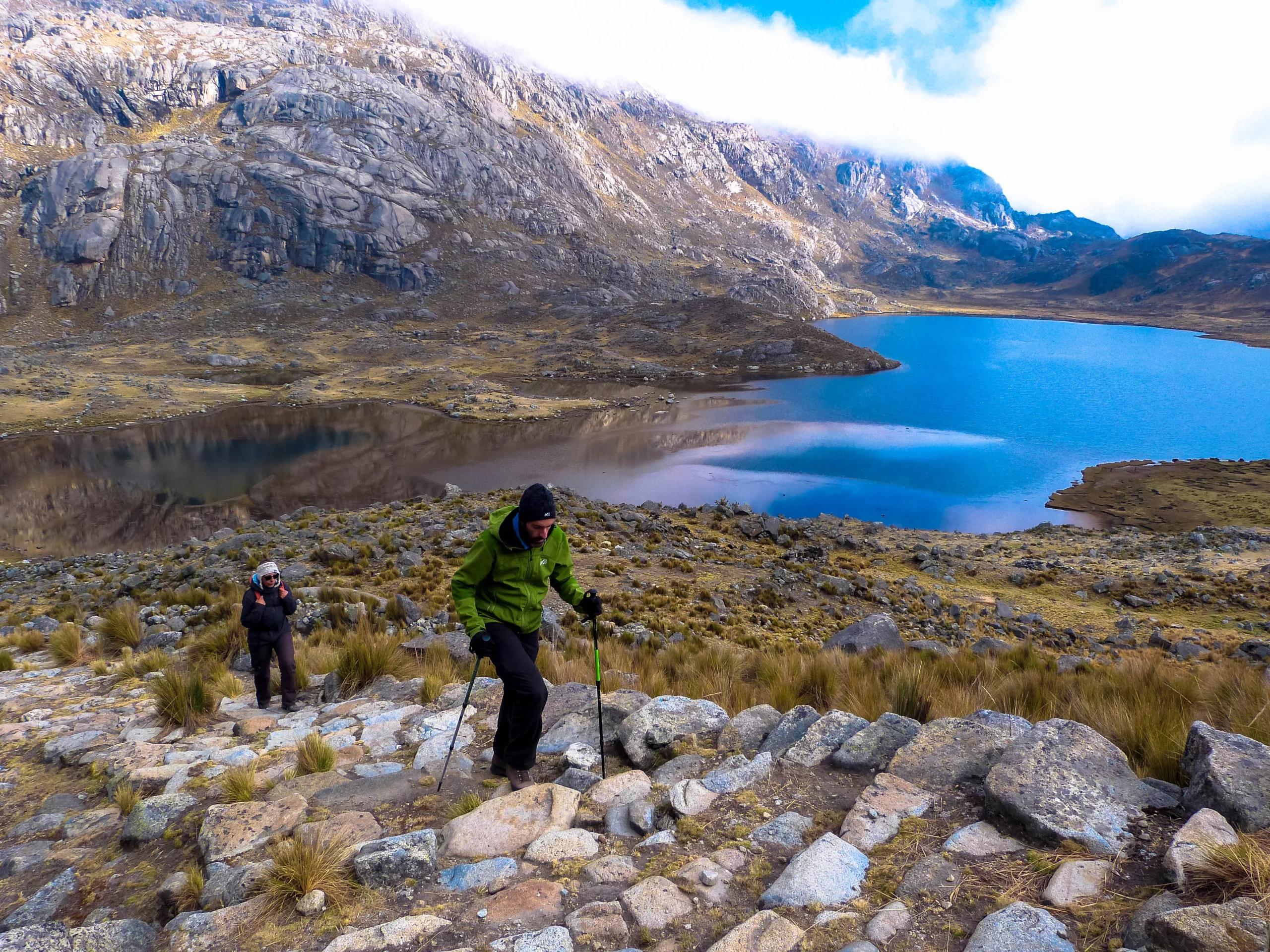 Randonneurs gravissant un escalier inca, avec la laguna Escalera en arrière-plan, dans la cordillère Pariacaca au Pérou.